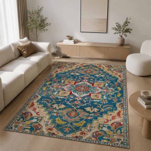 فرشینه دکوراتیو طرح قفقازی سنتی با زمینه آبی خوش‌رنگ و نقوش هندسی کرم و قرمز، پهن شده روی پارکت چوبی روشن در یک اتاق نشیمن با دکوراسیون مدرن، مینیمال و مبلمان رنگ خنثی.